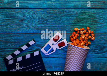Klappe, Gläser und Popcorn auf blauem Hintergrund Holz Draufsicht mit Copyspace Stockfoto