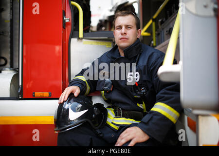Foto der jungen Feuerwehrmann mit Helm Blaumann sitzt in fire truck Stockfoto