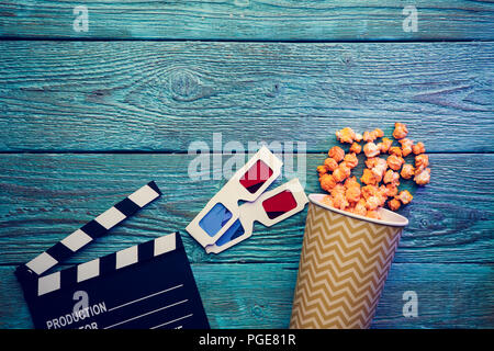 Klappe, Gläser und Popcorn auf blauem Hintergrund Holz Draufsicht mit Copyspace Stockfoto
