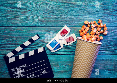 Klappe, Gläser und Popcorn auf blauem Hintergrund Holz Draufsicht mit Copyspace Stockfoto