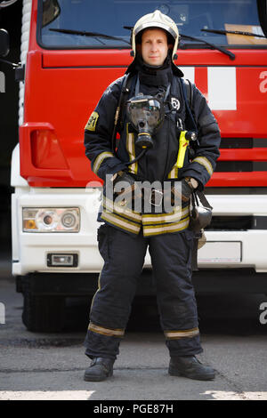 Foto im vollen Wachstum der Feuerwehrmann auf dem Hintergrund der Fire Engine Maschine am Bahnhof Stockfoto