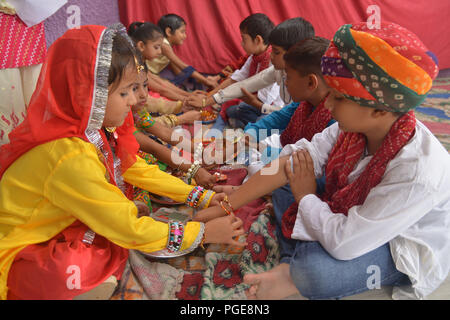 Ajmer, Indien. 25 Aug, 2018. Ein indisch-hinduistischen Mädchen Bindungen rakhis, oder heilige Gewinde, am Handgelenk ihres Bruders als symbolische Geste während der "Raksha Bandhan' Festival in Ajmer, Rajasthan, Indien, 25. August 2018. "Raksha Bandhan' feiert das Verhältnis zwischen den Brüdern und Schwestern. Foto von shaukat ahmed Credit: shaukat Ahmed/Pacific Press/Alamy leben Nachrichten Stockfoto
