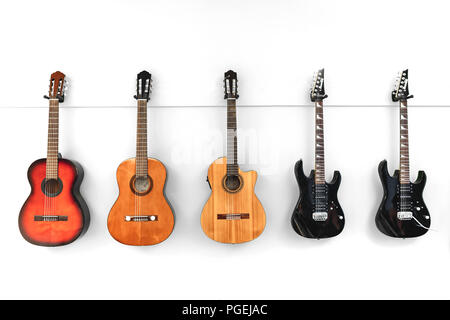 5 klassische, akustische, elektrische und Spanische Gitarren hängen an einer weißen Wand Stockfoto