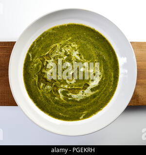 Brennnessel creme Suppe in einer weißen Schüssel auf ein Holz und Hochglanz weiß Hintergrund. Stockfoto