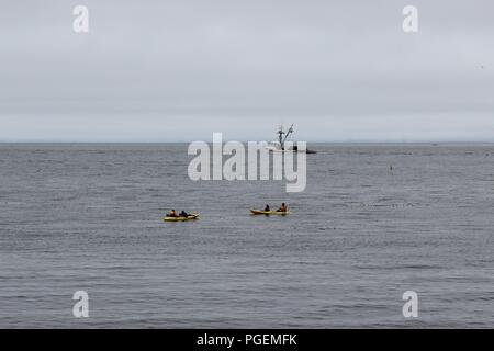 Kajakfahrer in Monterey Bay als Krabbenkutter verläuft in der Nähe Stockfoto