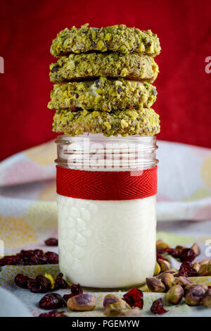 Cranberry Shortbread mit weißer Schokolade und Pistazien, auf ein Glas Mix in einem Marmeladenglas mit roter Schleife geschmückt gestapelt. Stockfoto