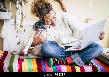 Echten besten Freunden fröhliche Frau mit Laptop arbeiten auf der Terrasse zu Hause, während Hug Ihre beste Liebe und Freunde smiling dog pug zu seiner Linken sitzen. co Stockfoto