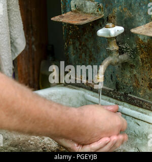 Wasser fließt von einer retro Sanitär in ein altes Waschbecken, in dem ein Mann seine Hände wäscht. Vintage Waschbecken im Freien. Selektive konzentrieren. Für instagram für Stockfoto