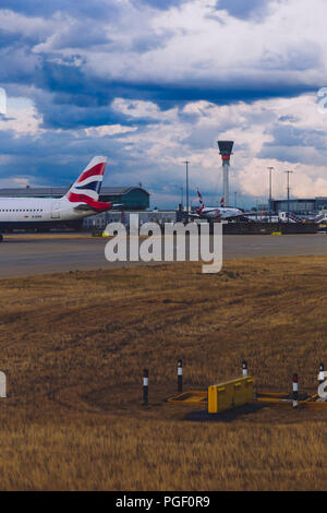 LONDON, Großbritannien - 10. August 2018: die Aussicht auf den Flughafen Heathrow mit stürmischen Himmel und British Airways Flugzeuge auf ihren Messeständen Stockfoto