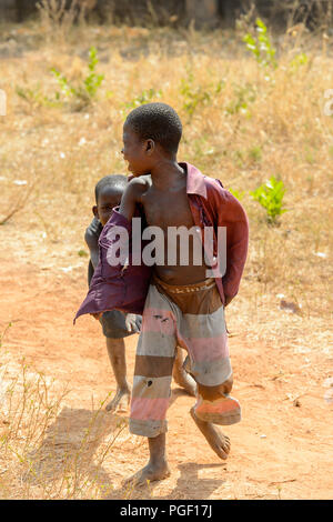 GHANI, GHANA - Jan 14, 2017: Unbekannter Ghanaischen kleines Mädchen versteckt sich hinter den Jungen in einem lokalen Dorf. Ghana Menschen leiden unter der Armut aufgrund der schlechten Stockfoto