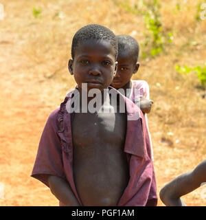 GHANI, GHANA - Jan 14, 2017: Unbekannter Ghanaischen kleines Mädchen versteckt sich hinter den Jungen in einem lokalen Dorf. Ghana Menschen leiden unter der Armut aufgrund der schlechten Stockfoto