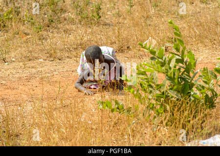 GHANI, GHANA - Jan 14, 2017: Unbekannter Ghanaischen kleines Mädchen versteckt sich hinter einem Busch in einem lokalen Dorf. Ghana Menschen leiden unter der Armut aufgrund der schlechten e Stockfoto