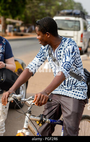 ACCRA, GHANA - Jan 8, 2017: Unbekannter ghanaischen Mann reitet ein Fahrrad auf der Straße. Menschen in Ghana Leiden der Armut aufgrund der wirtschaftlichen Situation Stockfoto