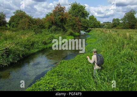 Ein Fliegenfischer Stengel einen Fisch auf den berühmten Fluss Itchen in Hampshire Stockfoto