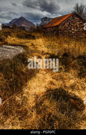 Alte Stein Zinn überdachte Gebäude mit Bergen im Hintergrund, Torridon, Schottland Stockfoto