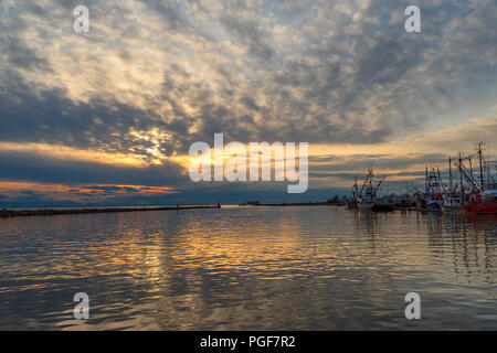 Fischerboote und Yachten sind auf der Pier am Ende des Tages in der Bucht. Scheint die Sonne hinter den Wolken und der Glanz spiegelt sich in den Wellen der t Stockfoto