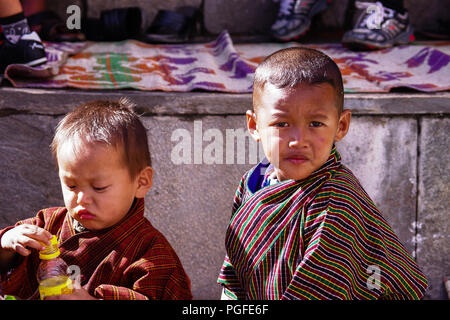 Zwei Jungen in der traditionellen Tracht als Gho bekannt. Über die bunte Thimpu Tshechu Festival, eine der bedeutendsten Feiern fotografiert von Bhutan Stockfoto