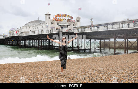 Brighton UK 26. August 2018 - eine junge Frau genießt selbst noch auf Brighton Beach trotz Wind und Regen da schlechtes Wetter fegt über der Südküste heute, aber die Prognose ist für es für August Bank Holiday Montag Foto von Simon Dack Credit: Simon Dack/Alamy Leben Nachrichten: Simon Dack/Alamy Leben Nachrichten zu verbessern. Stockfoto