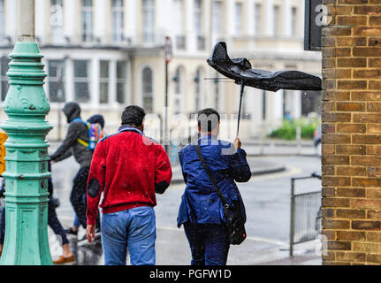 Brighton UK 26. August 2018 - Es ist ein Kampf der Sonnenschirme am Brighton Seafront in der Wind und der Regen da schlechtes Wetter fegt über der Südküste heute zu halten, aber die Prognose ist für es für August Bank Holiday Montag Foto von Simon Dack Credit: Simon Dack/Alamy Leben Nachrichten zu verbessern. Stockfoto