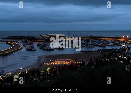 Lyme Regis, Dorset, Großbritannien. 20. August 2018. UK Wetter: Menschenmassen versammeln in Lyme Regis an einem bewölkten und nassen Abend Die Beleuchtung von über 4000 Kerzen entlang der legendären Cobb in der Abenddämmerung zu beobachten. Die Veranstaltung, die vom Rotary Club organisiert auch in diesem Jahr gedenkt die centenery vom Ende des Ersten Weltkrieges mit dem Ereignis, das Geld für die British Legion und lokale Nächstenliebe. Credit: PQ Images/Alamy Leben Nachrichten. Stockfoto