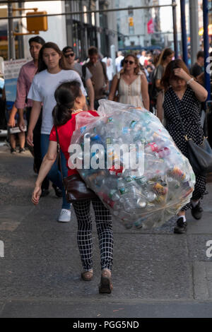 Eine anonyme asiatische Frau mittleren Alters auf der Fifth Avenue mit den Flaschen, die Sie von Abfalleimern gesammelt. Manhattan, New York City. Stockfoto