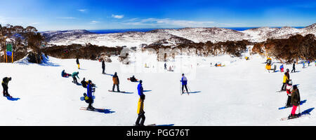 Skifahrer und Snowboarder auf schneebedeckten Pisten von Perisher Skigebiet Perisher Berg aus Zurück nach unten zum Tal auf einer sonnigen kalten Winter da Stockfoto