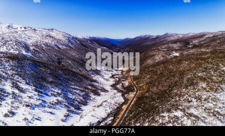 Winter Ski Saison hoch in den Bergen von Australien - Thredbo Valley. Thredbo River, Straße und Thredbo Skiort in luftaufnahme zwischen Tal Stockfoto