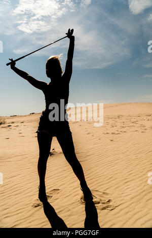 Silhouette einer Frau mit fliegenden Haare mit Golf Putter in der Wüste Stockfoto