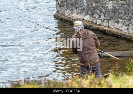 Mann angeln am Strand von Llyn Ogwen, Wales - UK. Stockfoto