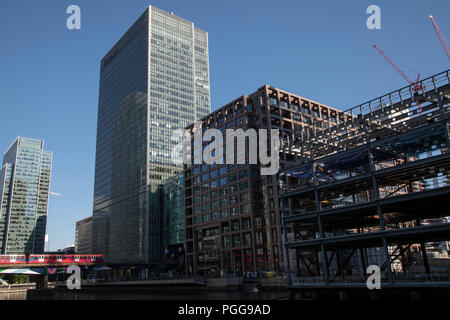 DLR-Zug auf die Hochbahn quert Mitte Dock in der Canary Wharf Financial District in London, England, Vereinigtes Königreich. Canary Wharf ist ein Bereich, der immer noch wächst, wie der Bau von neuen Wolkenkratzern fort. Die Docklands Light Railway ist eine automatisierte Light Metro System eröffnet 1987 die sanierte Docklands von London zu dienen. Stockfoto