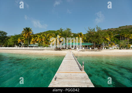 Ruhigen tropischen Strand mit weissem Sand, Palmen und das türkisblaue Karibische Meer Wasser auf Bequia Island in St. Vincent und die Grenadinen Stockfoto