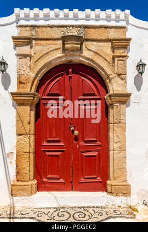 Rote Tür im traditionellen griechischen Haus im historischen Dorf Lindos auf Rhodos Insel. Griechenland. Stockfoto