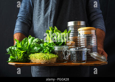 Grünen Gemüse und verschiedenen Getreidearten, die in Gläsern in der Hand Mann dunklen Hintergrund gesunde vegane Ernährung Konzept Stockfoto