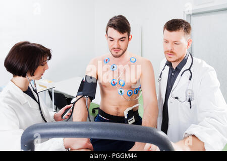 Athlet ist eine Herzbelastungsprobe in eine medizinische Studie, die von ihrem Arzt und Krankenschwester überwacht Stockfoto