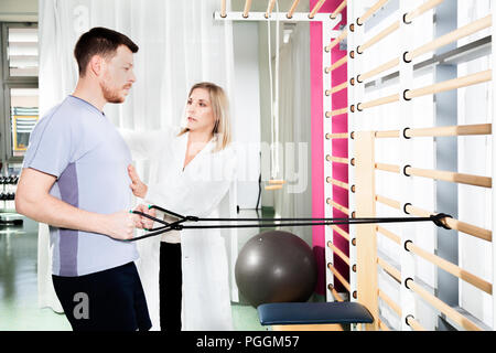 Arzt Physiotherapeut hilft, eine Bewegung des Patienten und die Funktion mit Gymnastik stretching wiederherzustellen und Übungen, um die Leistung zu verbessern Stockfoto