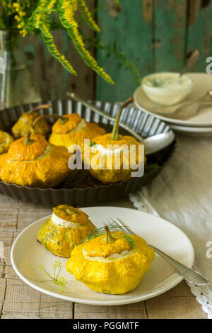 Pattypan Squash oder Kürbisse, gefüllt mit Ricotta mit Basilikum und Dill und serviert mit saurer Sahne Soße. Vegetarisches Essen, rustikaler Stil, selektiven Fokus. Stockfoto