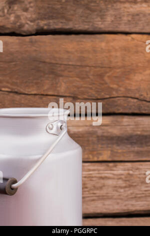 Stahl Milch kann. Alte hölzerne Schreibtisch Hintergrund. Stockfoto