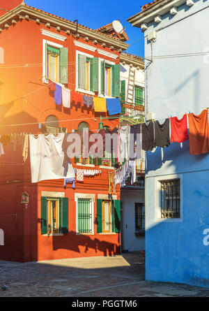 Wäsche aufhängen aus der typischen Häuser der Insel Burano, Venedig, Italien. Bunten Gebäuden und Wäsche trocknen auf der Straße in Burano, Venedig, Ital Stockfoto