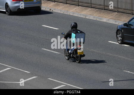 Eine deliveroo Rider liefern Lebensmittel auf dem Moped fahren entlang einer Schnellstraße mit Kopie Raum von oben genommen. Stockfoto