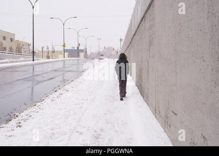 Der erste Schnee des Jahres. Ein unbekannter junger Mann oder Frau, allein, von der Rückseite, ist zu Fuß in den Schnee. Stockfoto