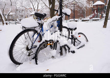 Der erste Schnee hat sich auf alles, was während der Nacht gefallen. Zwei Fahrräder sind von Schnee in einem öffentlichen Park. Stockfoto