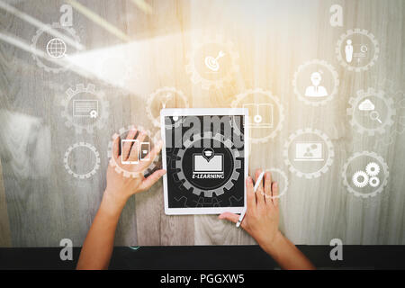 E-Learning mit angeschlossenem Getriebe Zahnräder verbunden Diagramm virtuelle Dashboard. nach oben Blick auf Designer Hand arbeiten mit digitalen Tablet Computer auf hölzernen Schreibtisch Stockfoto