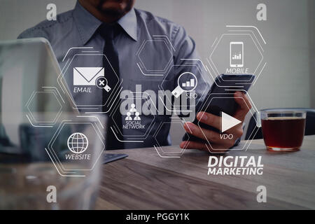 Digitales Marketing Medien (Website, E-Mail, Social Network, SEO, Video, Mobile App) in virtuellen Bildschirm. Erfolg Geschäftsmann hand mit Smart Phone, Ziffer Stockfoto