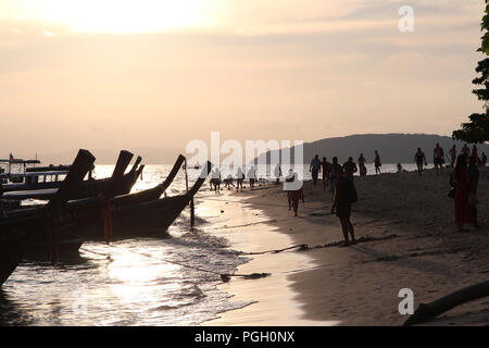 Sonnenuntergang und Silhouette Menschen und lange Boote auf Ao Phra Nang Beach, Railay, Krabi, Thailand Stockfoto