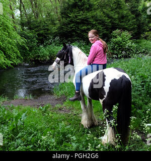 Junge Mädchen auf piebald Pferd durch die sechs Kilometer Wasser, Ballyclare, County Antrim, Nordirland. Stockfoto