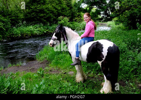 Junge Mädchen auf piebald Pferd durch die sechs Kilometer Wasser, Ballyclare, County Antrim, Nordirland. Stockfoto