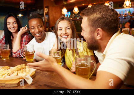 Gerne mit Freunden in der Bar sitzen, trinken Bier mit Snacks und Suchen an einer der Kerle, Lachen mit lustigen Geschichte, die er erzählt hat. Die Menschen genießen. Stockfoto
