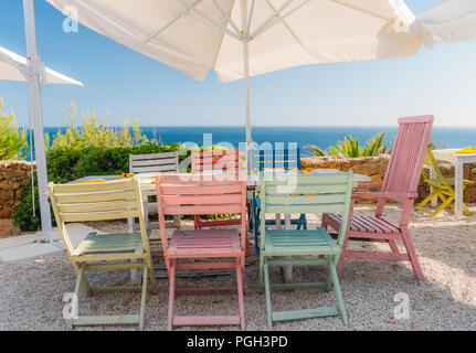 Buntes Holz- Stühle und Tisch in einem Sonnenschirm mit Blick auf den Ozean in Portugal. Stockfoto