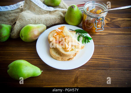 Stücke Brot mit Süßem hausgemachte Marmelade aus Birnen und Äpfel in eine Platte auf einem Holztisch Stockfoto