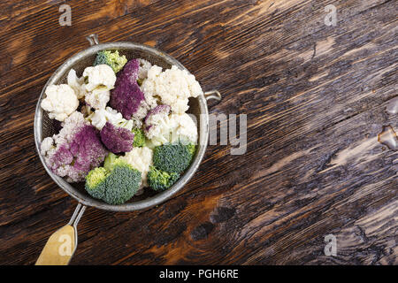 Blumenkohl verschiedene Farben in ein Sieb auf braunem Holz- Tabelle, Ansicht von oben Stockfoto